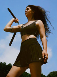 Model showcasing Orbit Bra with contrast stitching and soft-fit elastic band against a blue sky.
