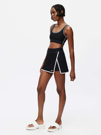Model showcasing the stylish Court Skort 2.5" in black, featuring silicone gripper band and hand-embroidered OV signature.