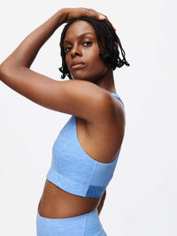Model showcasing the Doing Things Bra in blue, featuring mesh backing and Outdoor Voices logo.