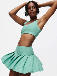Model showcasing the Doing Things 3" Skort, featuring a pleated design and built-in shorts in a vibrant mint green.
