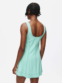 Back view of a model wearing the Energy Dress in mint green with A-line silhouette and contrast stitching.