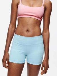 Model showcasing the Gemini 3" Short in light blue, featuring silicone gripper band and signature Outdoor Voices logo.