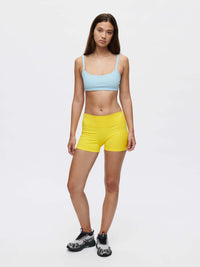 Model wearing Gemini 3" Short in bold yellow with a blue crop top against a plain background.
