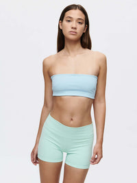 Model wearing the Love Bra bandeau top in blue paired with mint green shorts for a stylish athletic look.