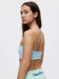 Woman wearing the Love Bra in light blue from the back, showcasing the bandeau style and sleek design.