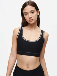 Model wearing an Orbit Bra, a medium-impact sports bra featuring OV logo and contrast stitching.