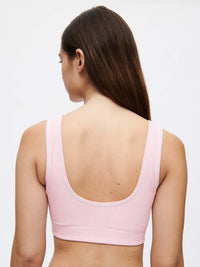 Back view of a model wearing the Orbit Bra in pink, showcasing its soft fit and comfortable style.