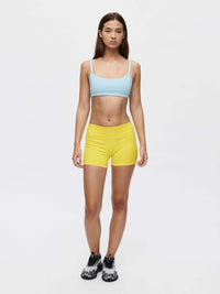 Model wearing a blue Solar Bra with yellow shorts, showcasing medium support and adjustable straps.