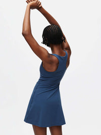 Back view of a model wearing the Volley Dress, showcasing its fit-and-flare silhouette in deep blue.