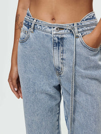 Close-up of Cowgirl Jean featuring salt wash finish, mid-rise waist, and removable lasso-style denim belt.