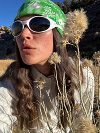 Woman wearing RecFleece 1/4 Zip layered under sunglasses and headband, posing amidst dry grass in nature.