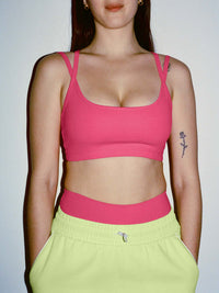 Model wearing Apple Bra in Pink with plunging neck and intersecting straps, styled for everyday wear.