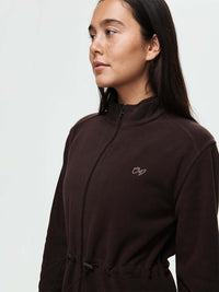 Model in a close-up view wearing Boulder Dress in Dark Brown with adjustable waist toggles and embroidered signature.