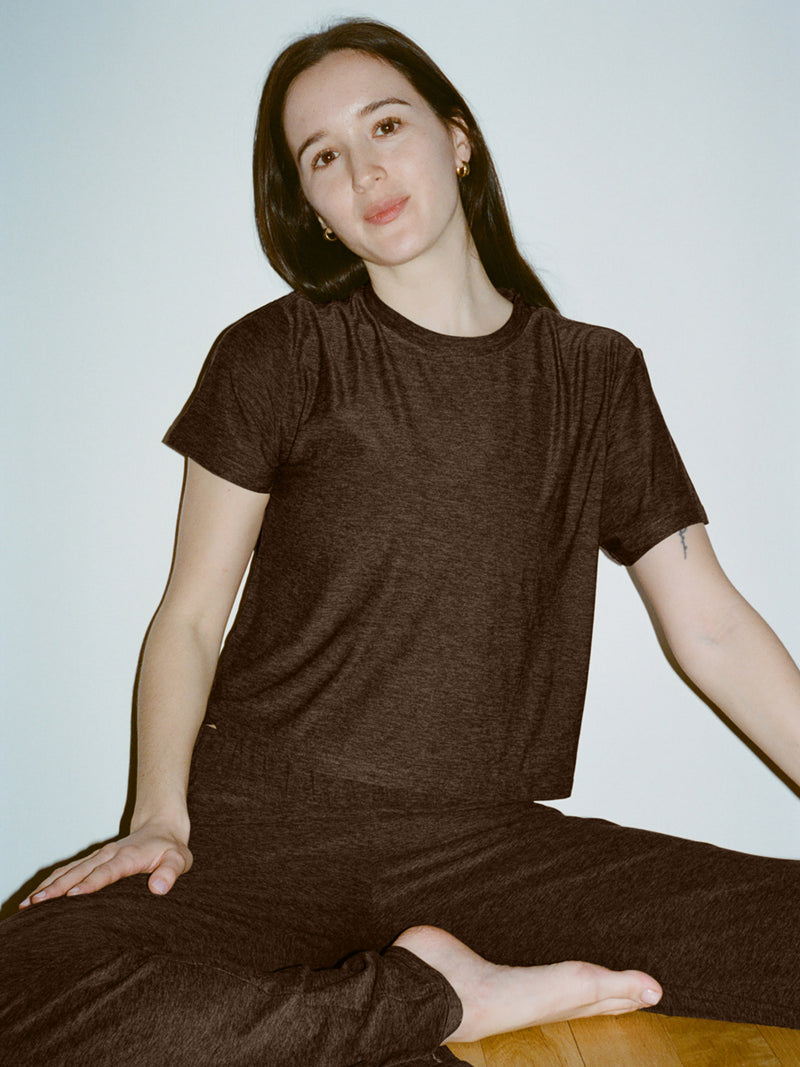 Model sitting in a relaxed pose wearing CloudKnit Boxy Shortsleeve in Charcoal, featuring a comfort-first, cropped design.