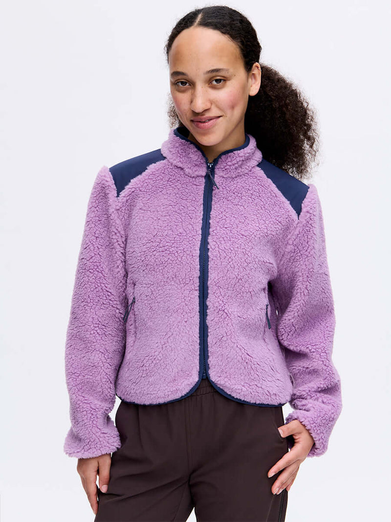 Model smiling in Candy Fleece Jacket, light purple with navy technical panels, for everyday wear.