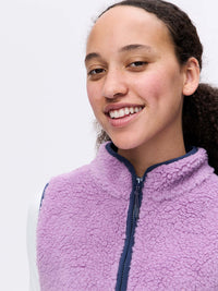 Model smiling in Candy Fleece Vest, light purple with a soft, cozy texture and zip front.