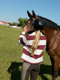 Woman wearing a Club Polo, interacting with a horse in a sunny field, for fall layering.
