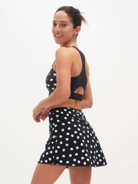 Model posing in Club Skort with polka dots, featuring a flared hem and built-in short.
