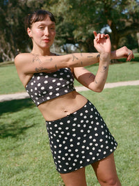 Model stretching in Club Skort with polka dots, featuring a playful design and built-in shorts.