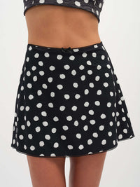 Model wearing Club Skort in black with white polka dots, featuring a cute bow at the waist.