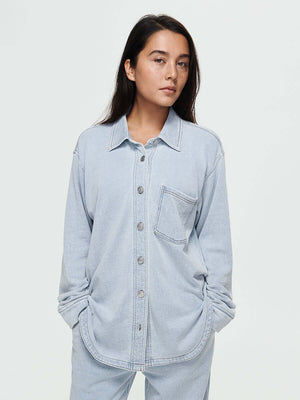 Model wearing Desert Shirt in light blue, oversized fit with brushed silver buttons and a curved hem.