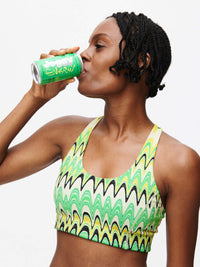 Doing Things Bra worn by a model sipping Joosy Energy drink, with its vibrant design and style.