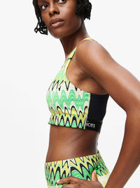 Woman wearing Doing Things Bra in vibrant green wave pattern, with mesh backing and Outdoor Voices logo.