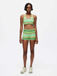 Model wearing Doing Things Bra with matching shorts in vibrant green zigzag pattern, for activewear.
