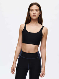 Model wearing Double Time Bra in Black with a double scoop design, styled for active movement.