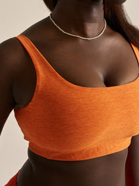 Close-up of model wearing Double Time Bra in vibrant orange, with a snug, low support fit for activewear.
