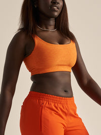 Model wearing Double Time Bra in Orange, with a snug fit and low support for everyday activities.