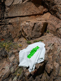 Flat lay of Energy Tee in mint green on rocky terrain, featuring a futuristic silicone print in Joggy Green.