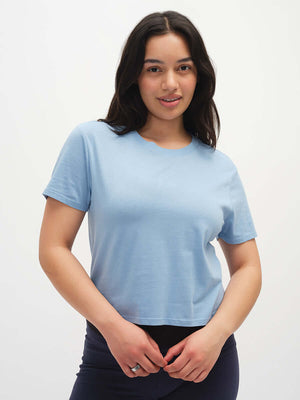 Model smiling while wearing Everyday Shortsleeve in Light Blue, featuring a relaxed fit and slight crop.