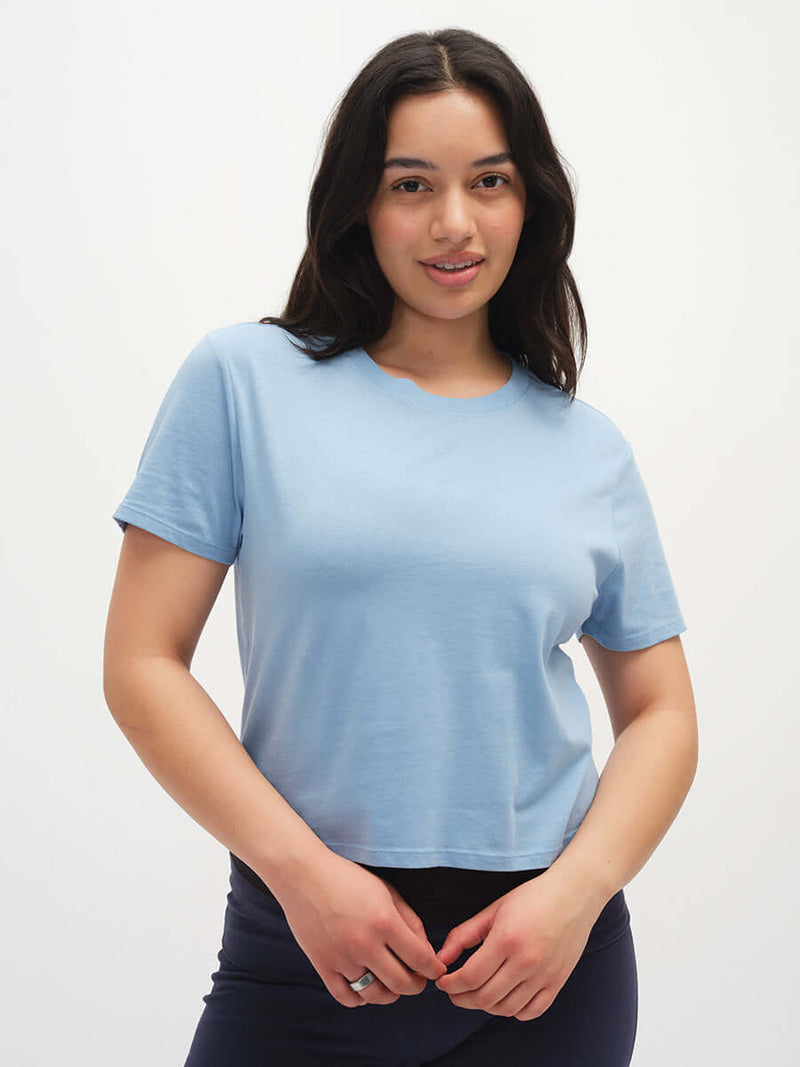 Model smiling while wearing Everyday Shortsleeve in Light Blue, featuring a relaxed fit and slight crop.