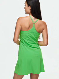 Model with The Exercise Dress in vibrant green, designed for active wear with adjustable straps and a flowing fit.