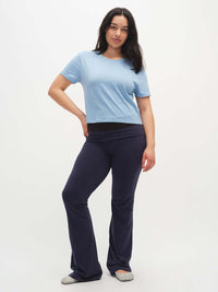 Model standing in Flared Legging in Navy with an extra-tall waistband, paired with a light blue top.