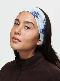 Model wearing Frosted Headband in blue with exclusive Elf Garden print, cozy fleece fabric for warmth.