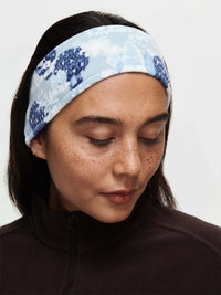 Woman wearing Frosted Headband in Light Blue, featuring exclusive Elf Garden print with pine trees and daisies.