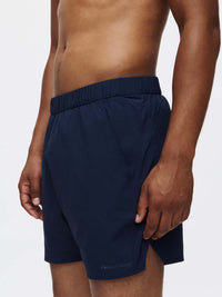 Model side view wearing High Stride 5" Short with Pockets in Navy, featuring an elastic waistband for comfort.