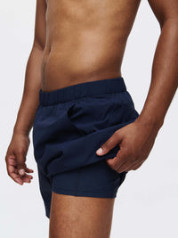 Model in profile wearing High Stride 5" Short with Pockets in Navy, with the lightweight fabric and elastic waistband.