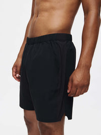 Model in profile wearing High Stride 7" Short with Pockets in Black, featuring front pockets and a comfortable elastic waistband.