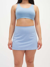 Model wearing LightSpeed Minimal 3" Skort in Light Blue with built-in shorts liner and phone pocket, styled for everyday use.