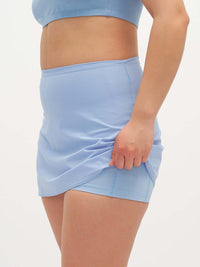 Side view of model wearing LightSpeed Minimal 3" Skort in Light Blue, featuring a built-in shorts liner.