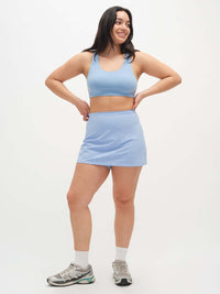 Model smiling in LightSpeed Minimal 3" Skort in Sky Blue, with built-in shorts liner for added comfort.