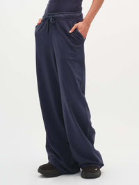 Model posing in Malibu Sweatpant in Navy, with wide leg design and side pockets.