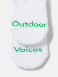 Close-up view of OV No Show Sock in White, showing bright green Outdoor Voices text.