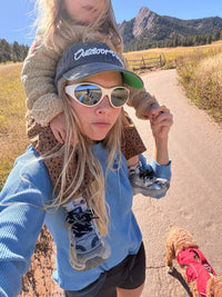 Woman carrying a child on her shoulders in a Waffle Longsleeve, enjoying a hike with a dog in a sunny outdoor setting.