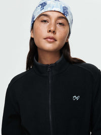 Close-up of model wearing Boulder Dress in Black with full zip and OV logo, styled for outdoor activities.
