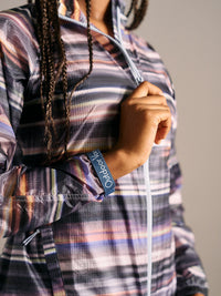 Close-up of model wearing Jog Jacket in multi-colored plaid, showing the elasticated cuff and branding detail.