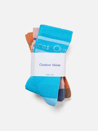 Flat lay of OV Club Crew Sock 3-Pack in blue, pink, and brown with moisture-wicking fabric and 'Doing Things' print.